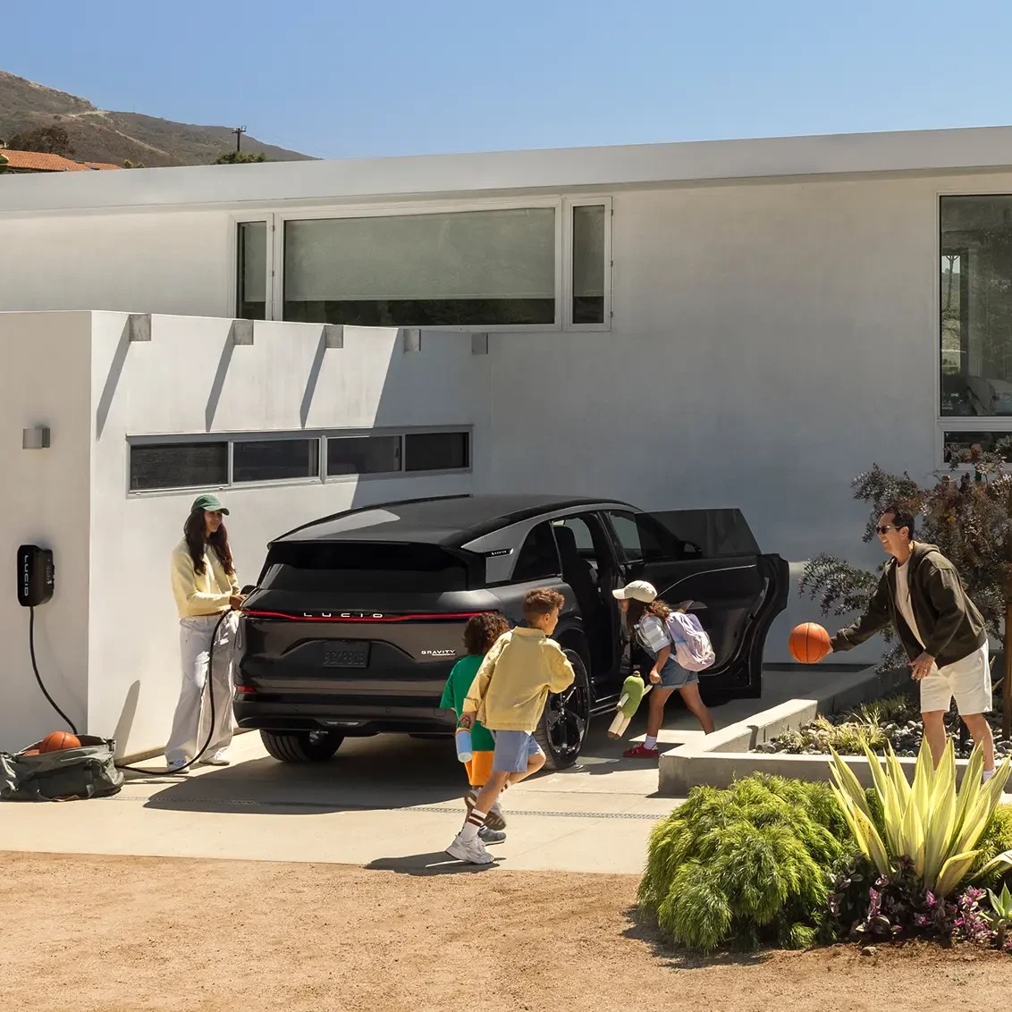 Lucid Gravity charging in a driveway, official press photograph.