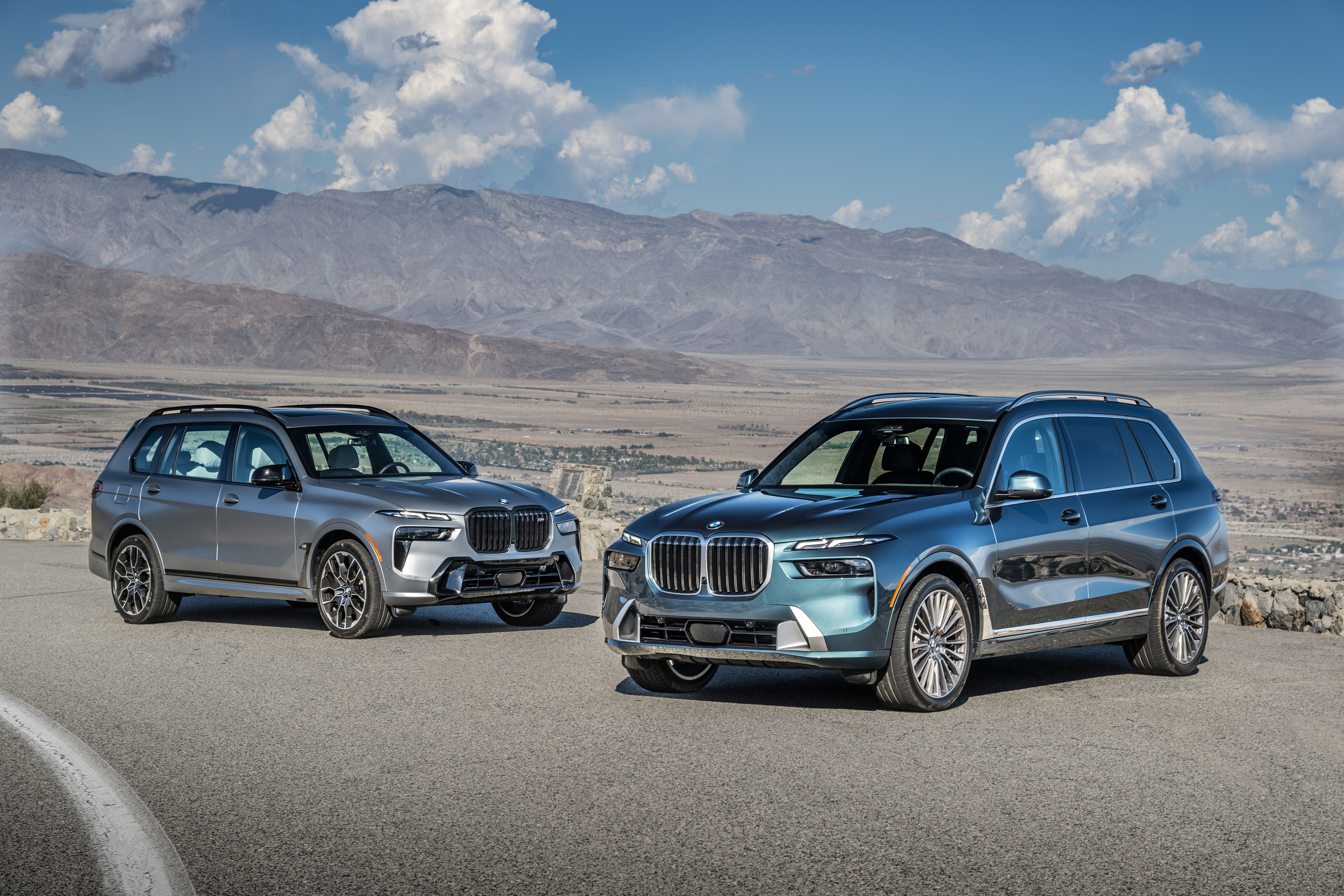 BMW X7 and Mercedes-Benz GLS luxury SUVs parked together in a desert landscape.