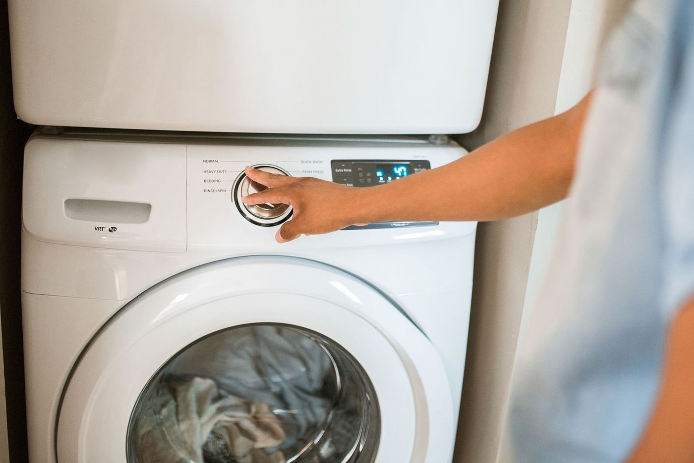 Hand turning the dial on a front-loading washing machine