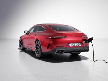 Rear studio view of a Mercedes-AMG GT 4-Door Coupe with a charging cable attached.