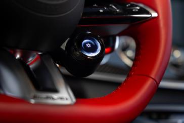 Close-up of the Mercedes-AMG GT 4-Door Coupe's steering wheel drive-mode dial, in red leather.
