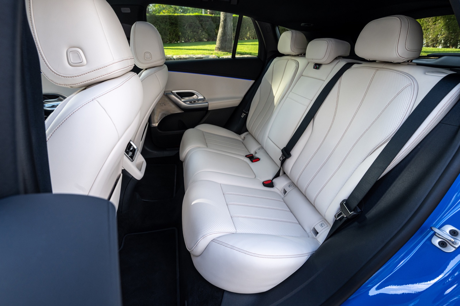 The GLC rear bench in white leather, seen through the open rear door of a blue press car.