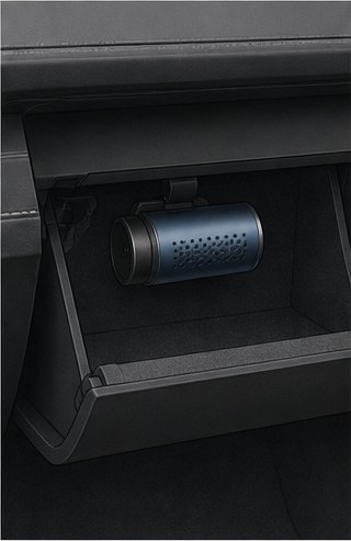 Illustration of a small cylindrical fragrance atomiser in a glovebox.