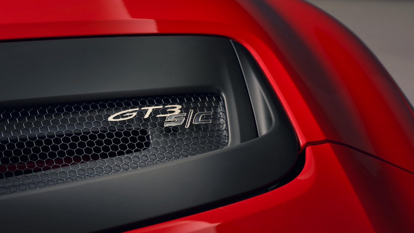 The GT3 S/C badge on the engine cover grille of a red Porsche 911.