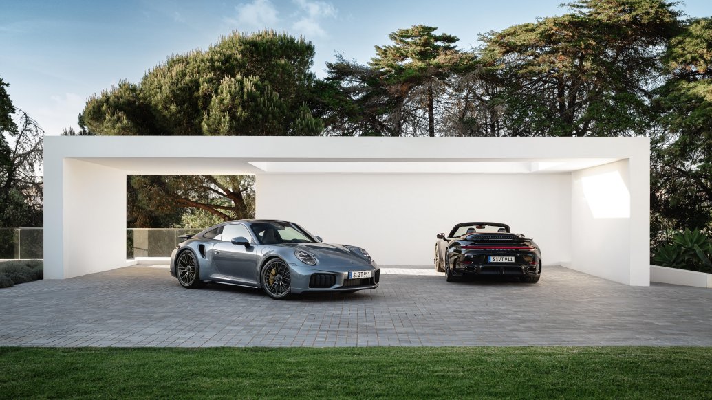 911 Turbo S Coupe and Cabriolet parked together outside a modern white building.