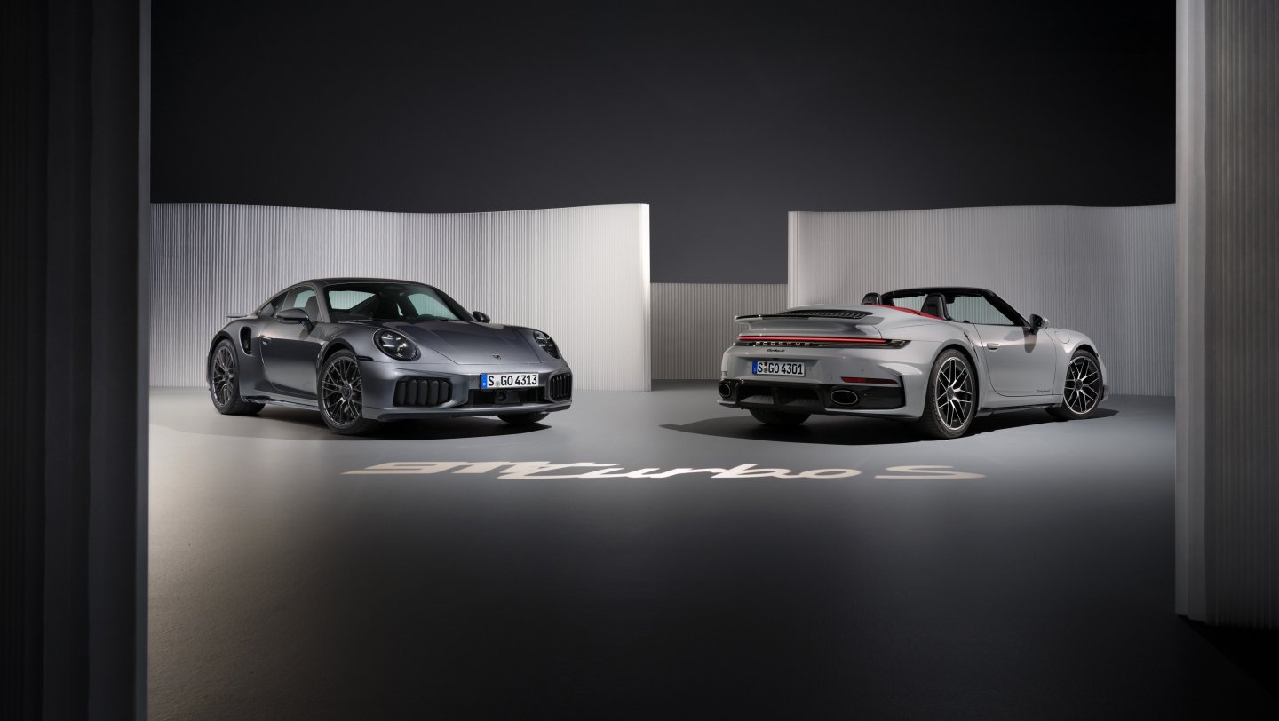 911 Turbo S Coupe and Cabriolet under spotlights, with 911 Turbo S lettering on the studio floor.