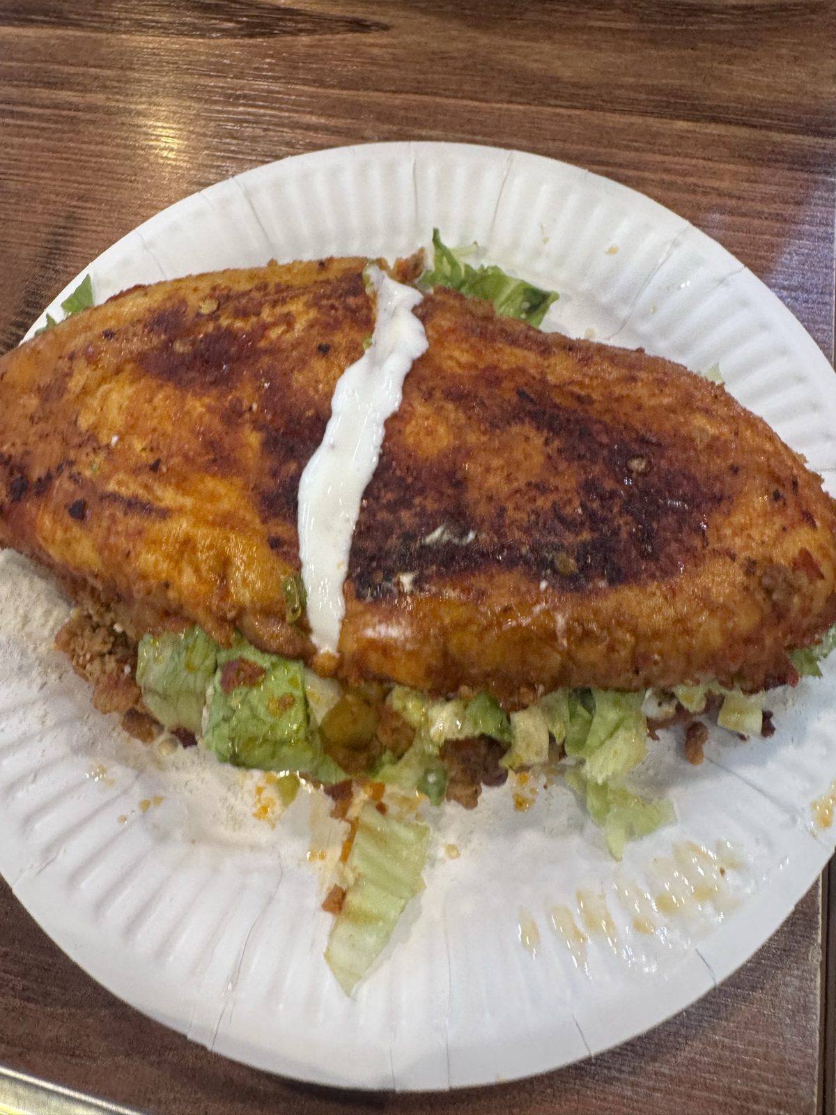 The pambazo whole, chile-red bread with a line of crema, lettuce spilling out.
