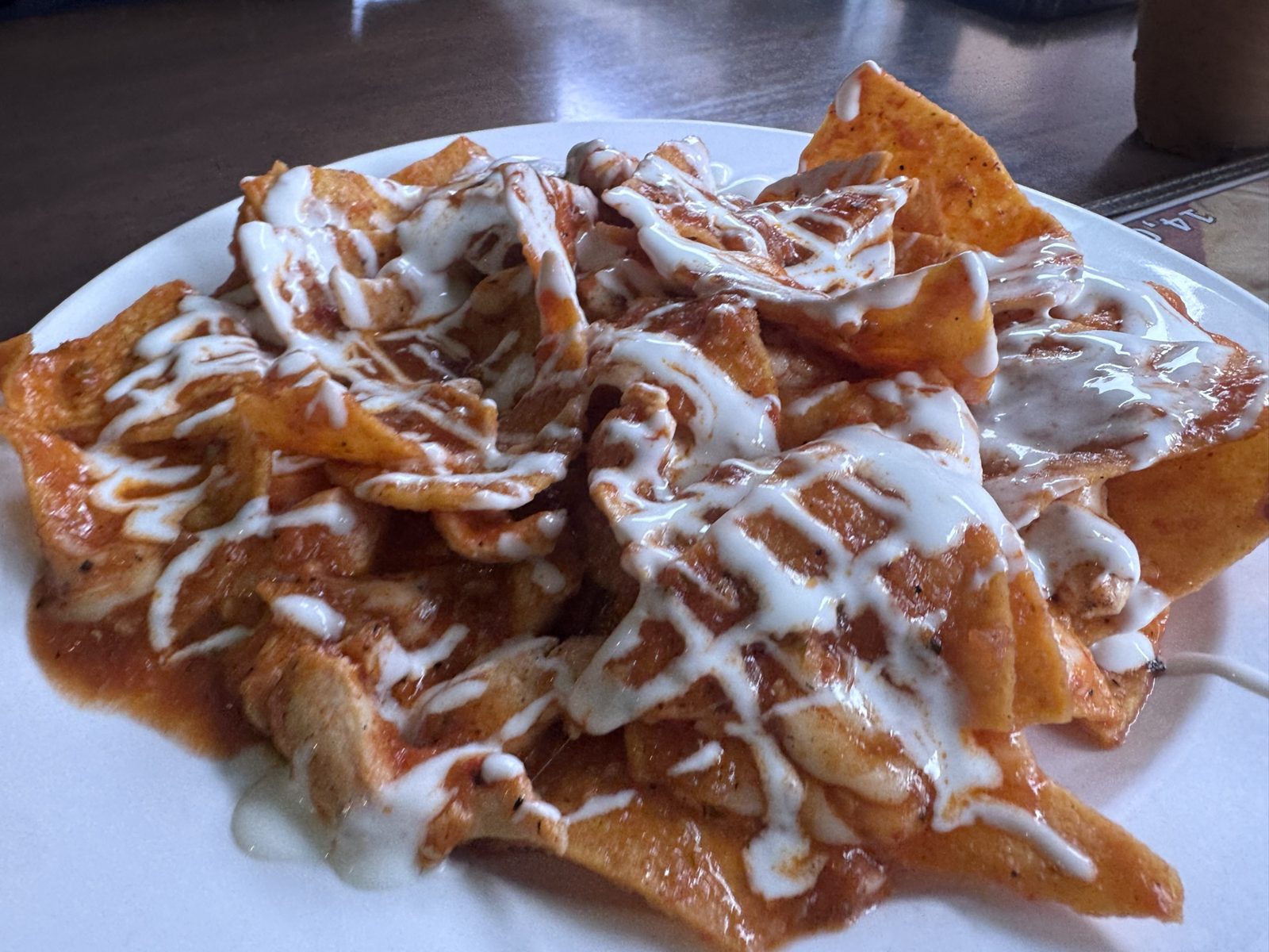 Chicken chilaquiles at Taco Amigo: tortilla chips in red salsa with drizzled crema.