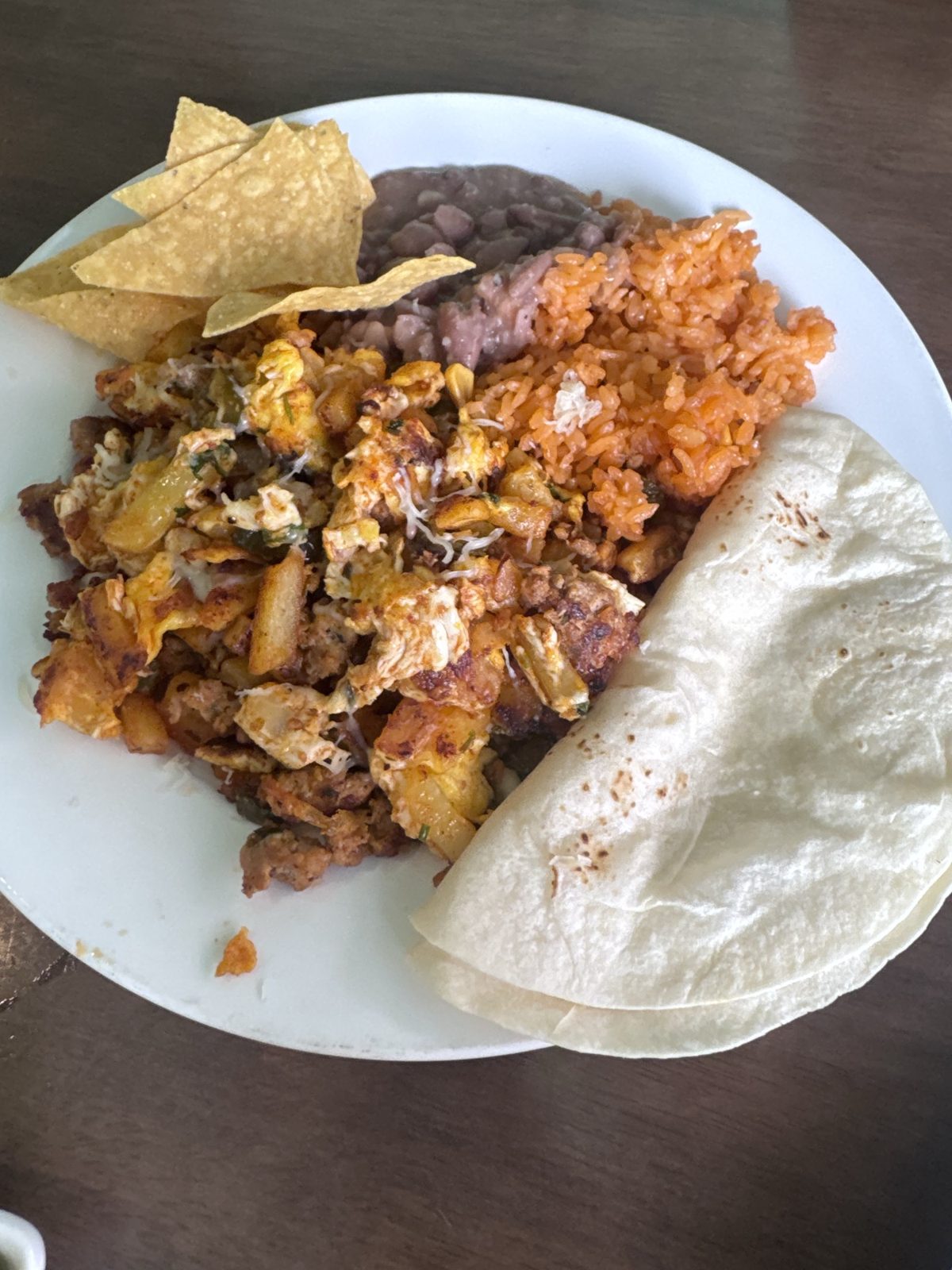 Chorizo con huevo at Taco Amigo with a folded flour tortilla, rice, beans and tortilla chips.