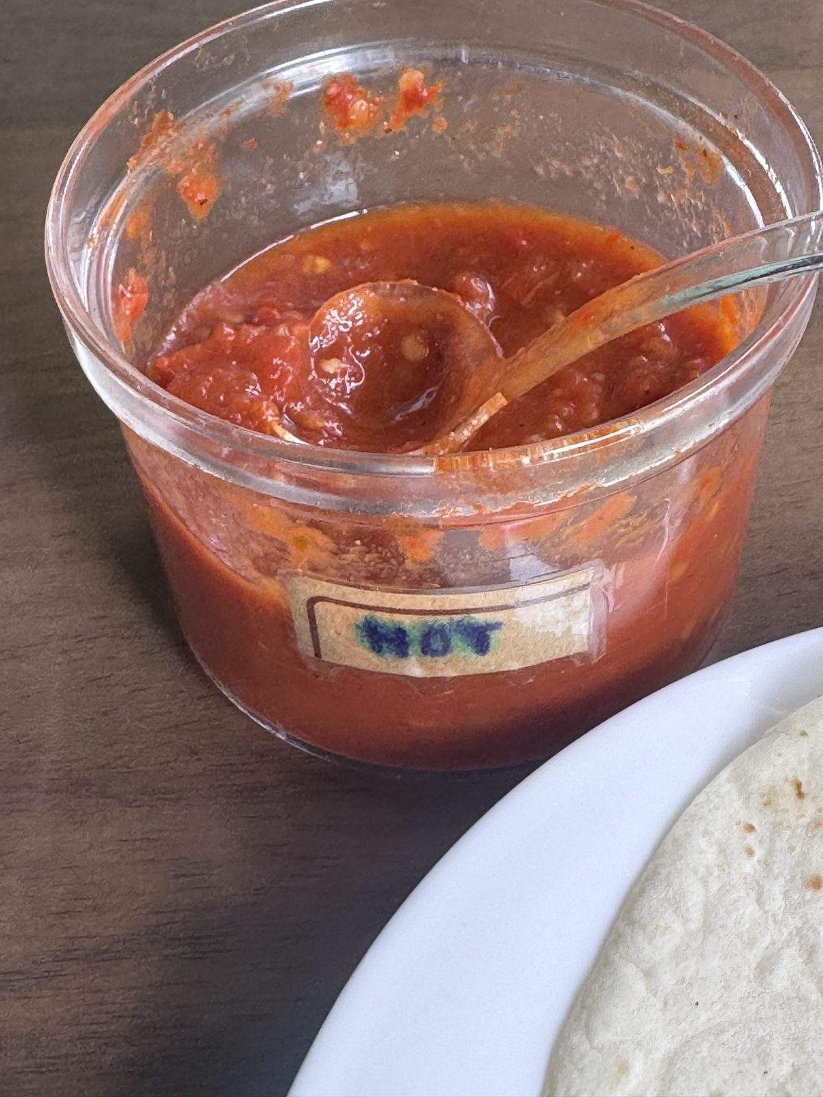A small jar of red table salsa labeled HOT at Taco Amigo.
