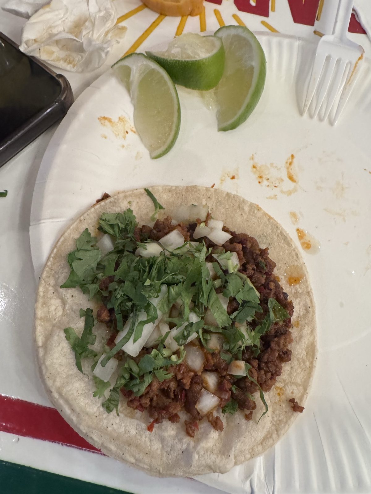 A chorizo taco at Villa Guerrero with onion and cilantro, lime wedges alongside.