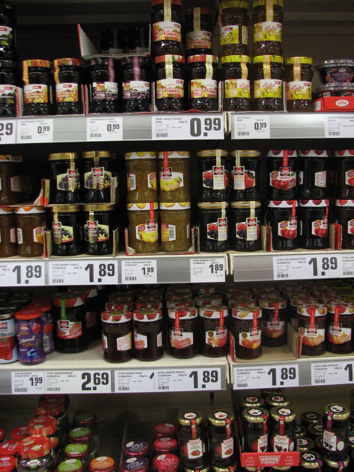 A real supermarket shelf densely stocked with many different jam and preserve brands