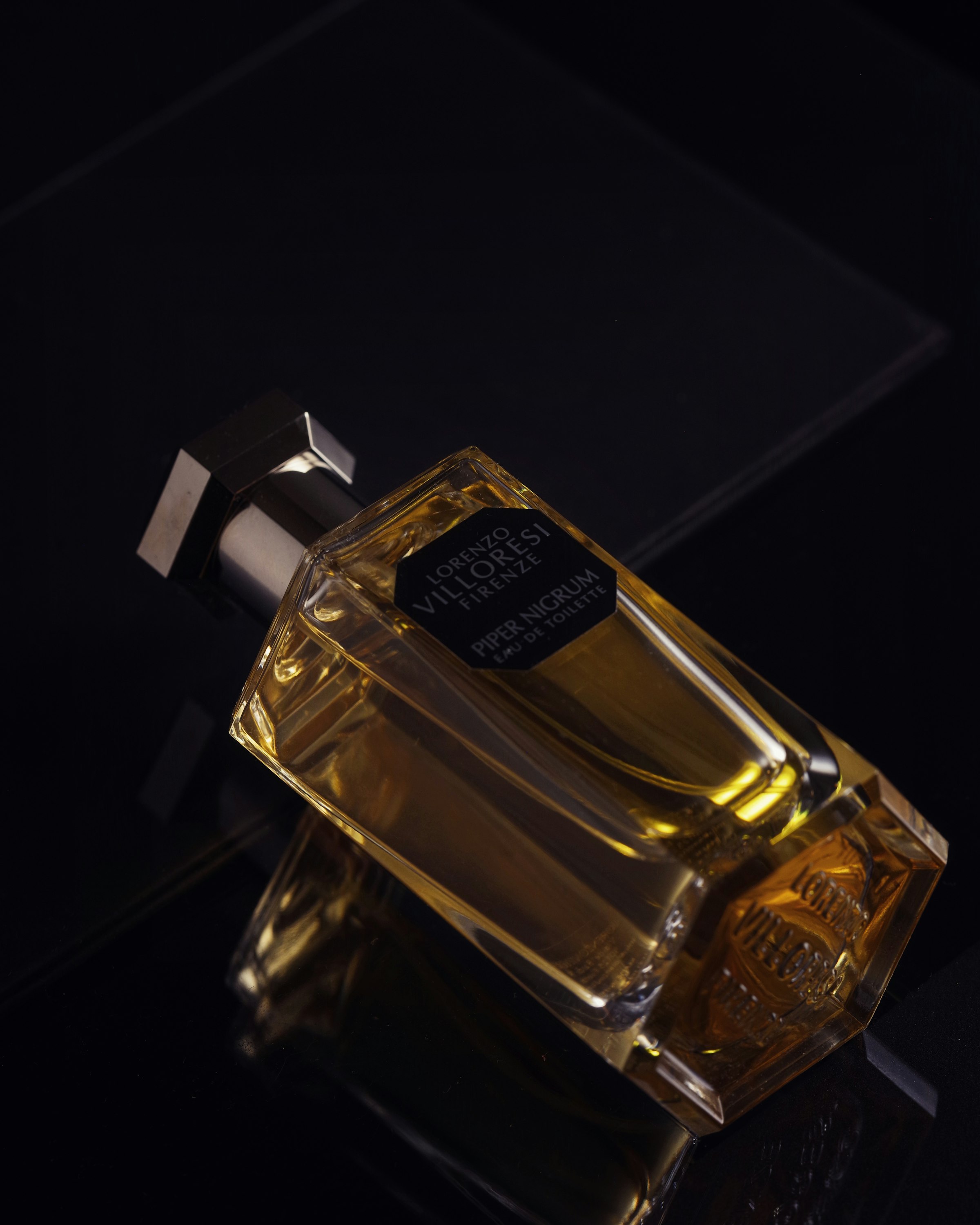 Amber fragrance bottle catching warm light, a real photograph.