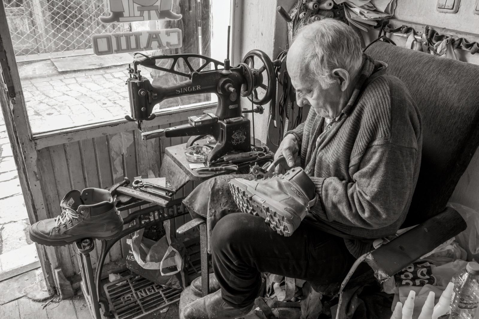 A cobbler repairing shoes by hand in an old workshop, Bitola, North Macedonia, 2025 — real photograph.