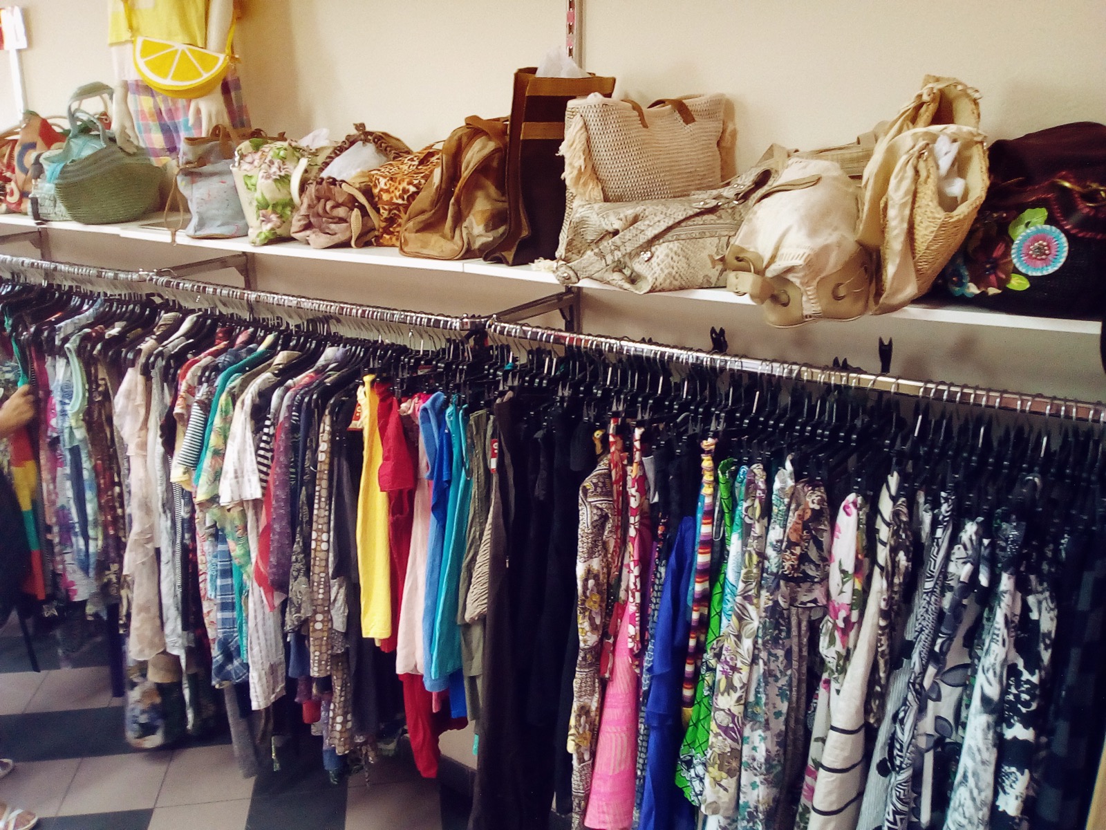 Racks of secondhand clothing and bags in a thrift store, Prague, real photograph.