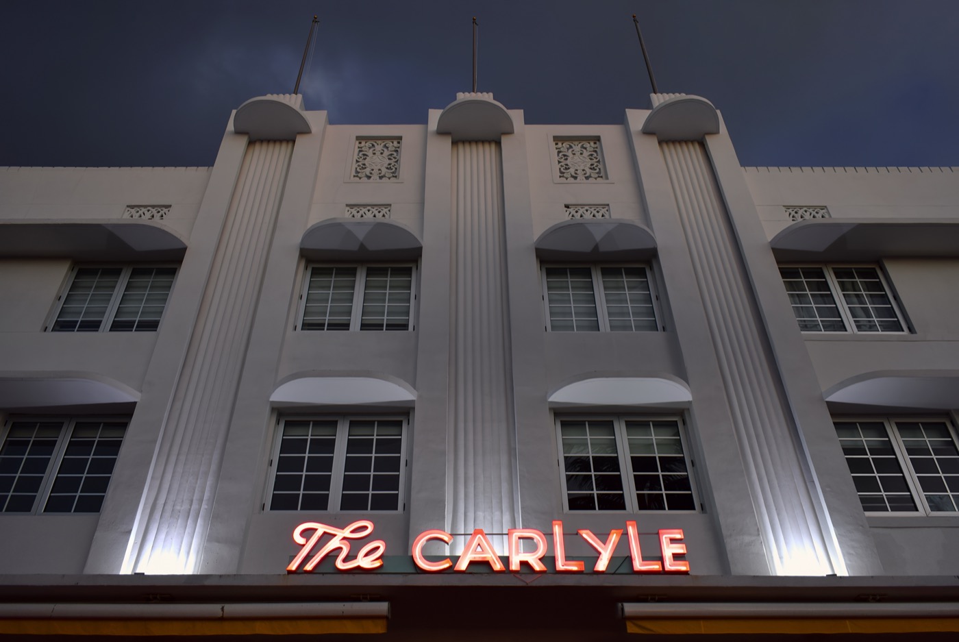 A vintage Art Deco neon hotel sign glowing in Miami Beach at night.