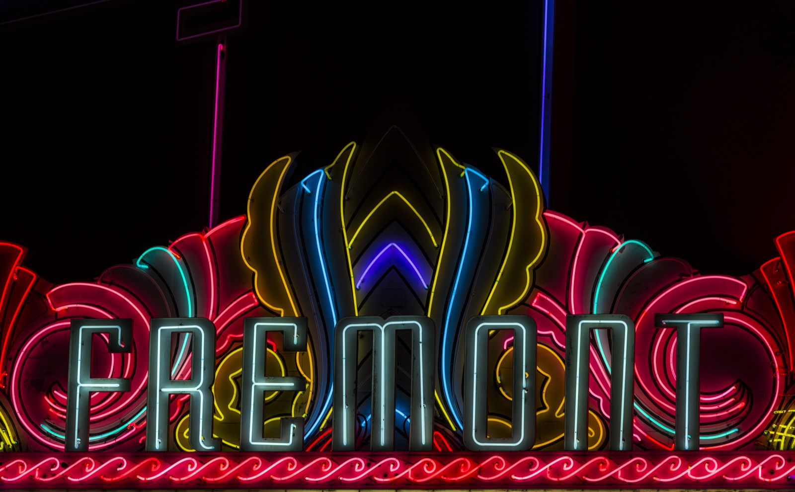 A classic neon movie theater marquee lit up at night.