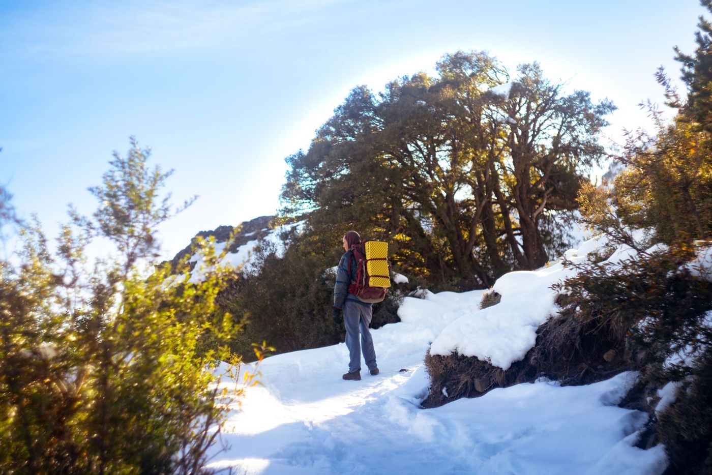 Hiker with a loaded pack walking a snowy trail