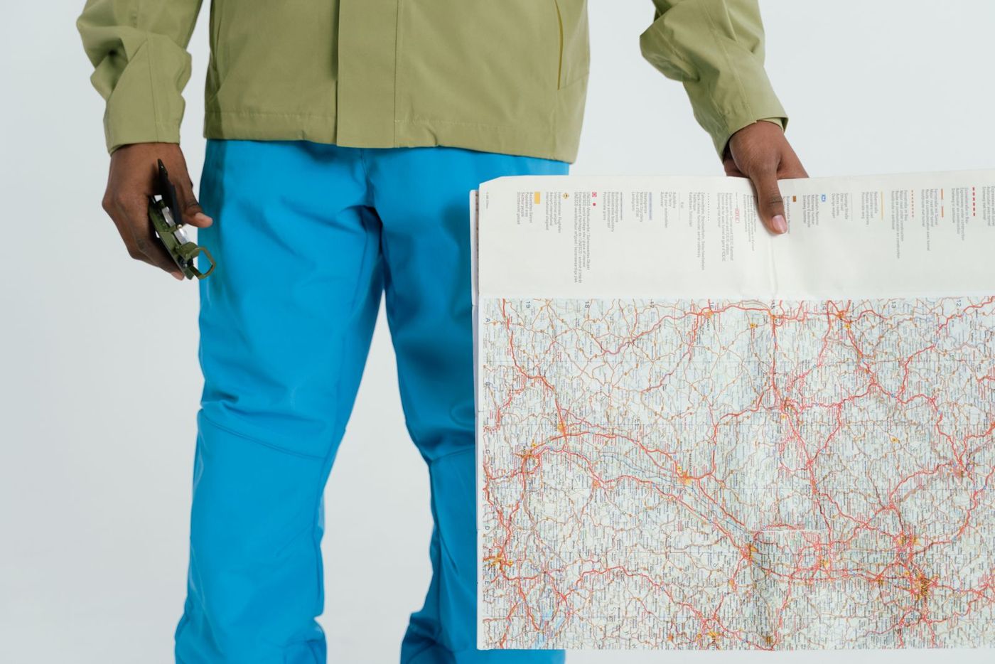 A person holding a paper map and a compass