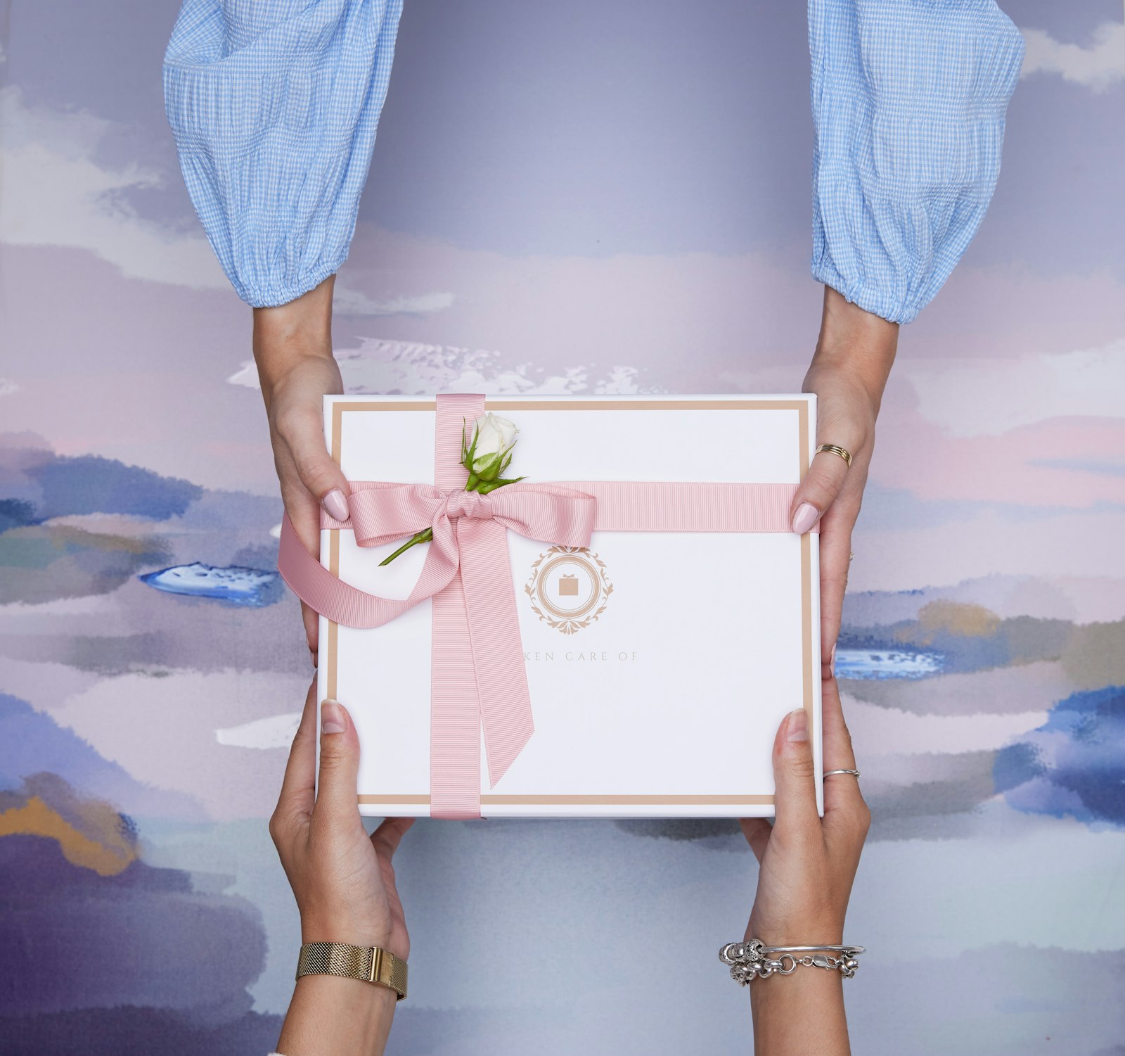 Two hands exchanging a wrapped wedding gift box