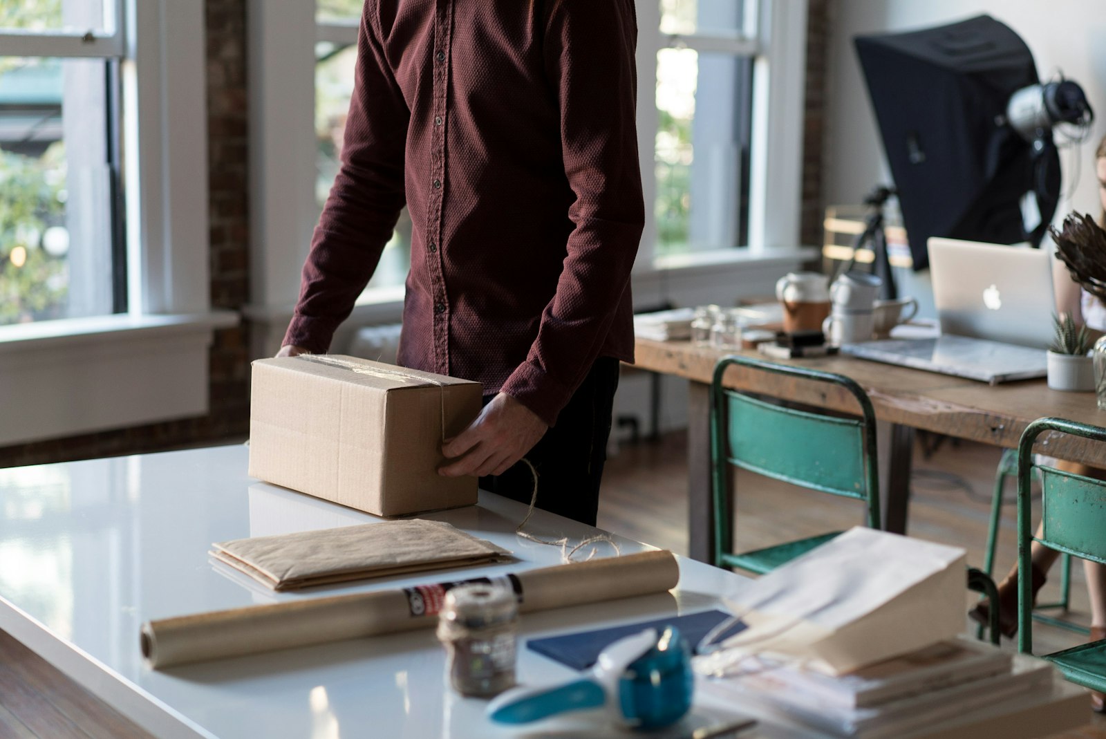 A person holding a plain cardboard shipping box, prepared for return