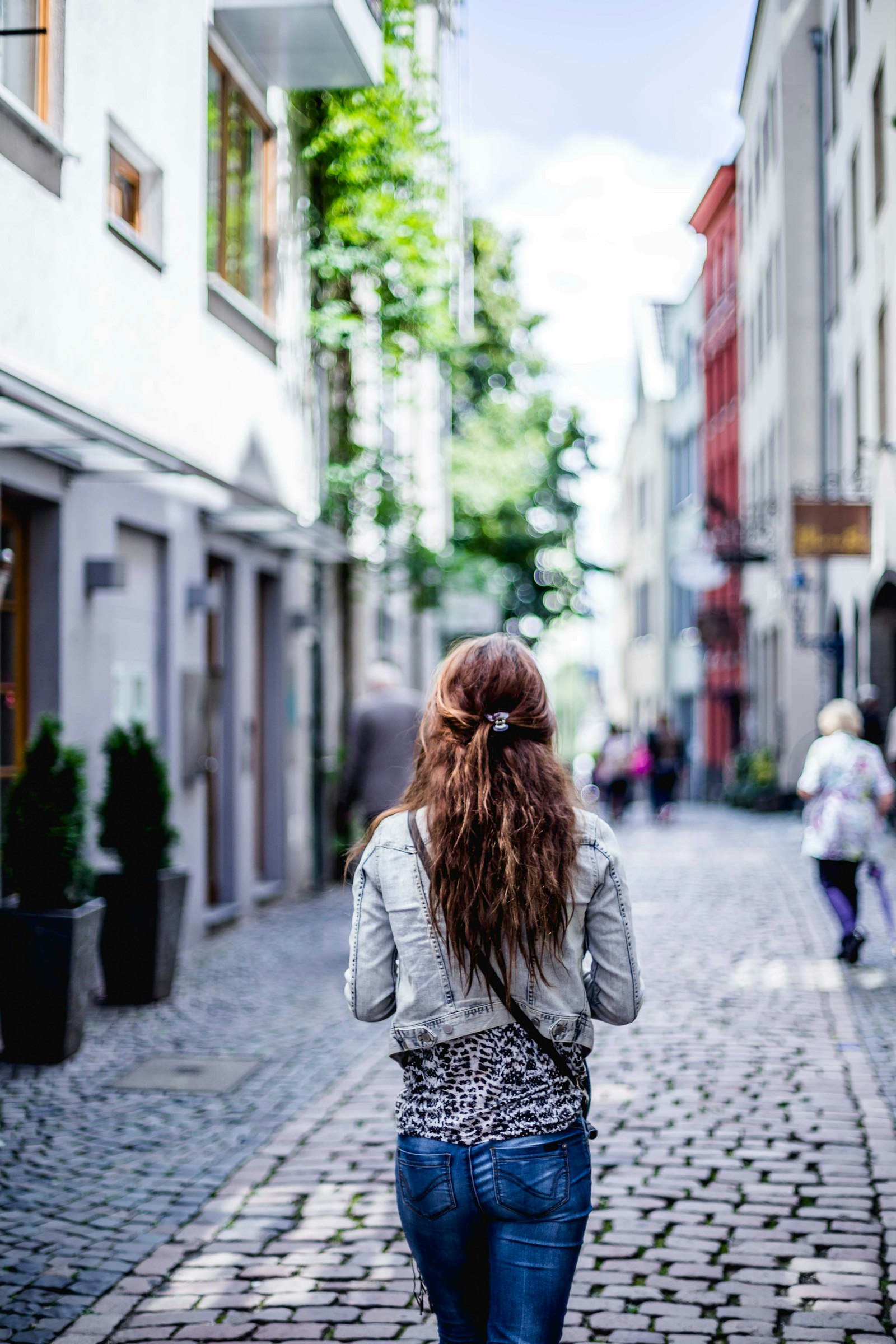 A person walking alone down a city sidewalk with headphones on